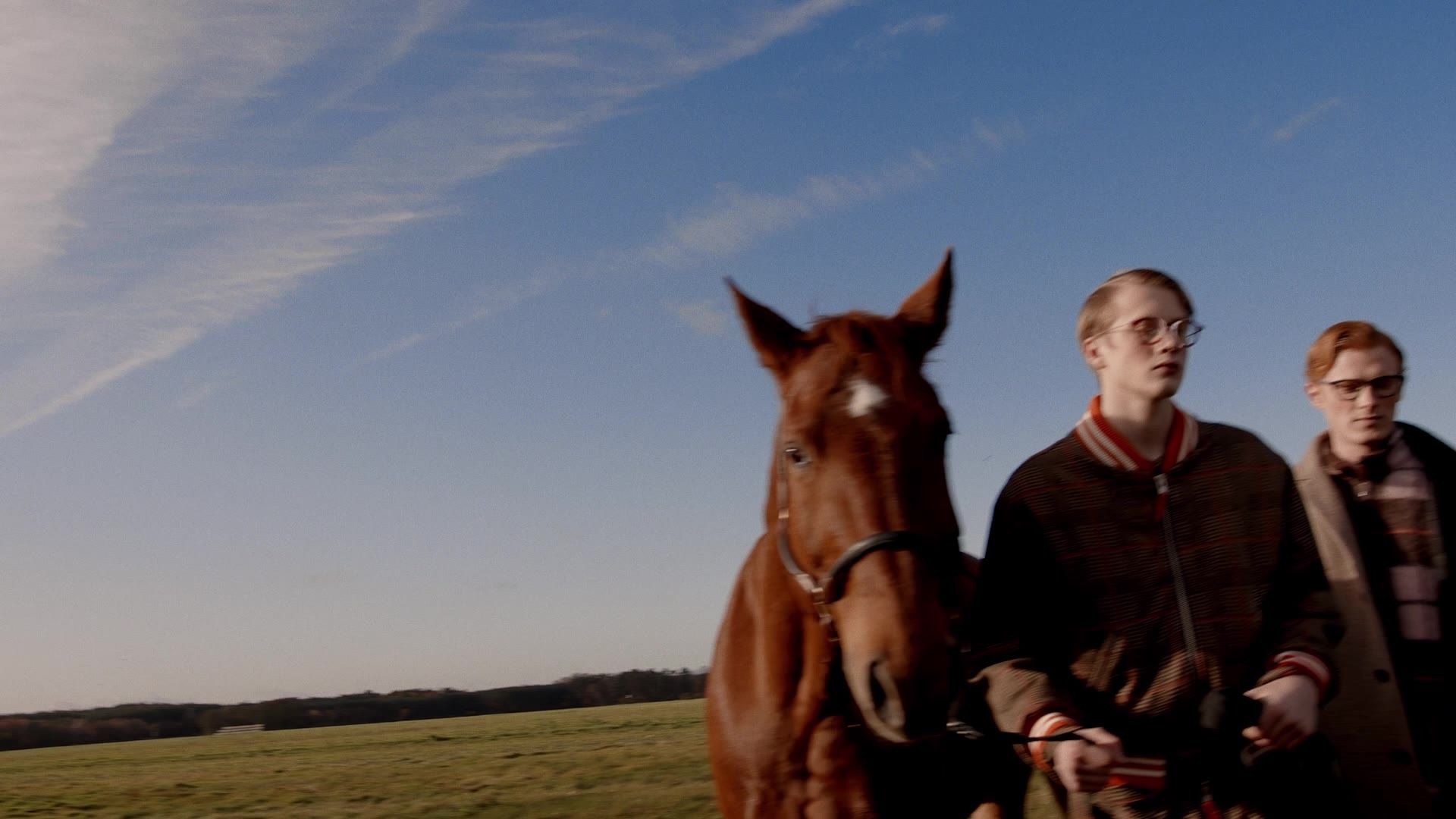 Still from the fashion film for Spectr x Lindberg: two men with a horse on a field